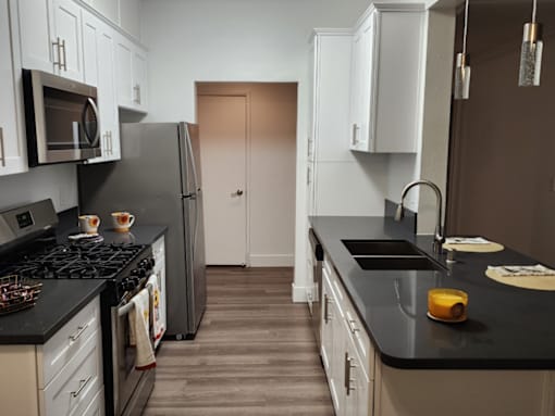 A kitchen with black countertops and white cabinets.