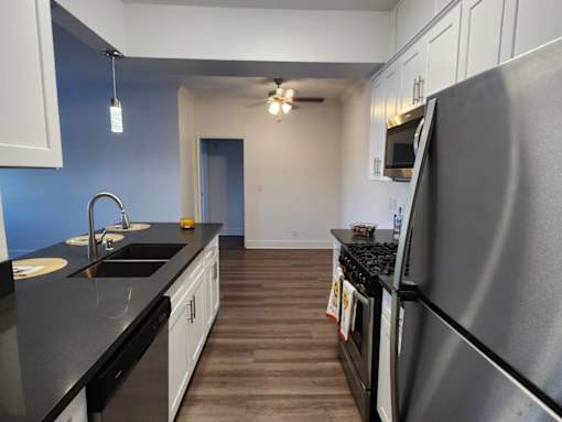 A kitchen with a black countertop and stainless steel appliances.