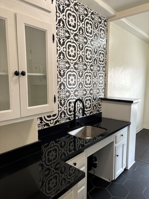 a black and white kitchen with a sink and white cabinets