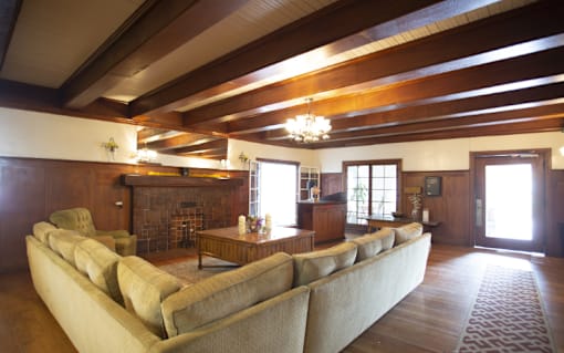 A large beige couch sits in a spacious living room with wood floors and a fireplace.