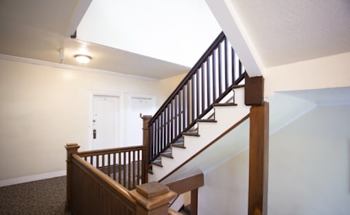 A staircase with a wooden handrail and a skylight above.