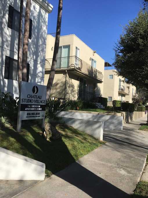 A sign for Chateau Studio Village is in front of a building.