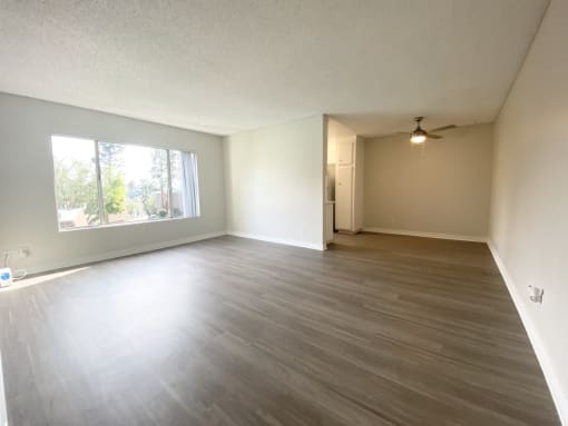 an empty living room with wood floors and a large window