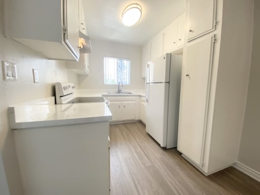 an empty kitchen with white cabinets and a white refrigerator