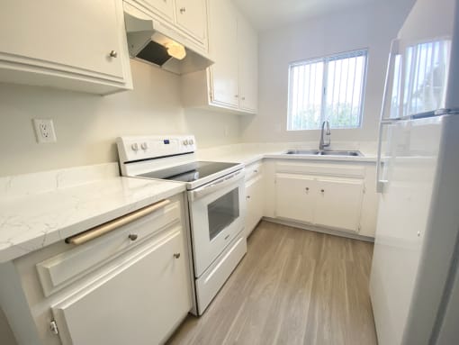 an empty kitchen with white appliances and white cabinets