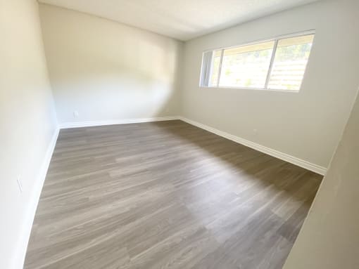 an empty room with wooden floors and a window
