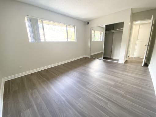 an empty living room with a wood floor and white walls