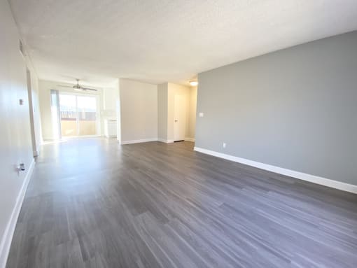 the living room and dining room of an apartment with wood flooring