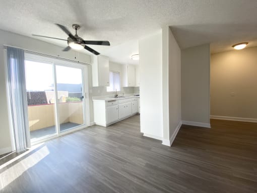 an empty living room and kitchen with a ceiling fan