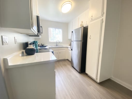 a kitchen with white cabinets and a stainless steel refrigerator