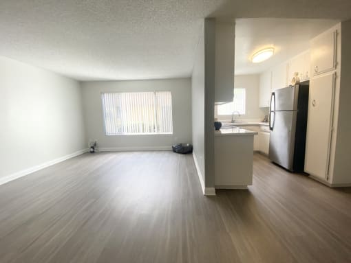 an empty living room and kitchen with a wood floor