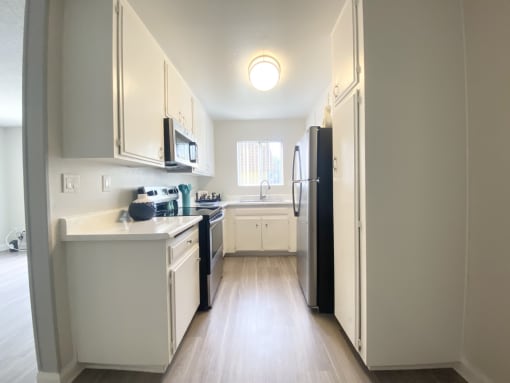 a kitchen with white cabinets and a black refrigerator