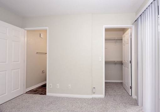an empty bedroom with a closet and a mirrored closet door