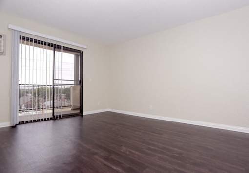 an empty living room with wood floors and a sliding glass door