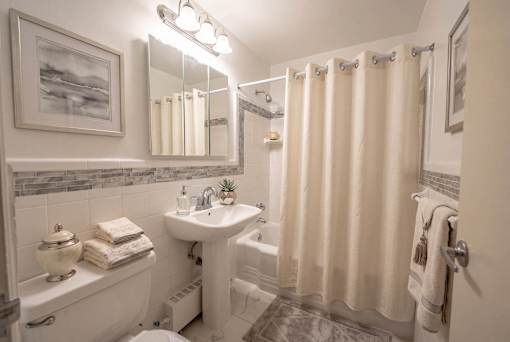 A white bathroom with a white tub, sink, and toilet.