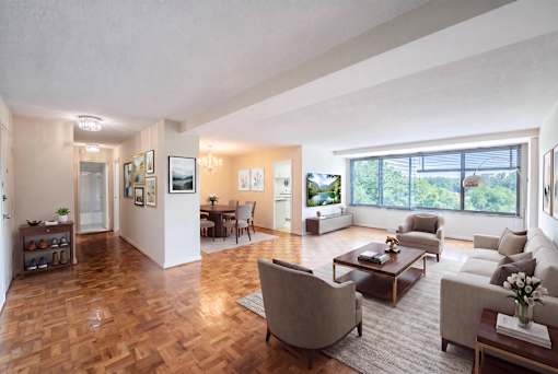 A spacious living room with a large window and a view of trees outside.