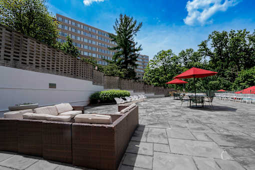 A patio with a red umbrella and a stone wall.