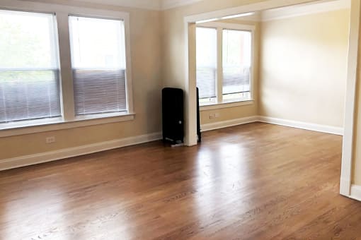 an empty living room with hardwood floors and three windows