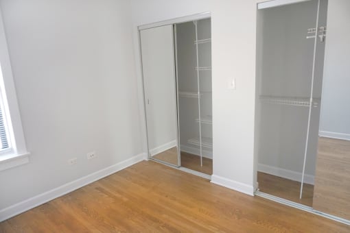 a bedroom with a wooden floor and a closet with glass doors
