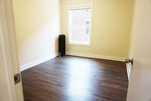 an empty room with a window and hardwood floors