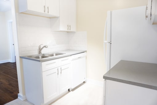 a small kitchen with white cabinets and a stainless steel sink