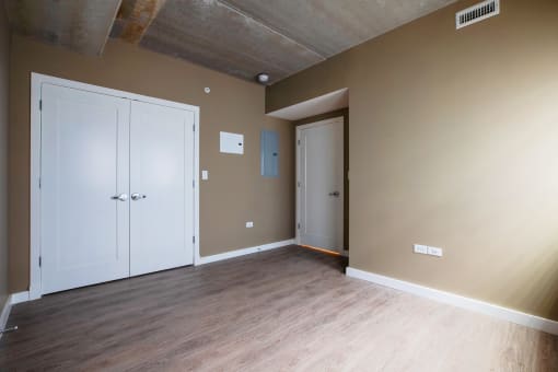 an empty room with wood floors and a concrete ceiling