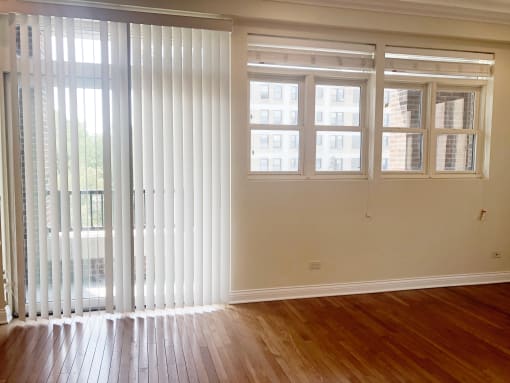 an empty living room with white blinds on the windows