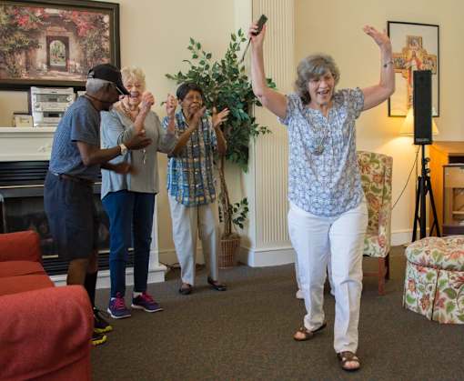 A group of people dancing in a living room.