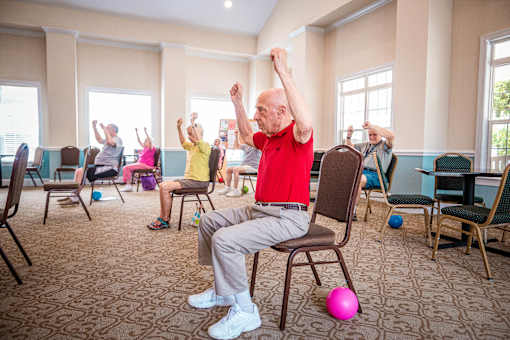 A group of elderly people exercising in a room.
