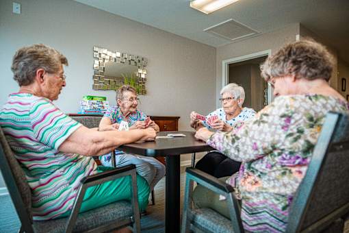Four elderly women sitting around a table playing a game.