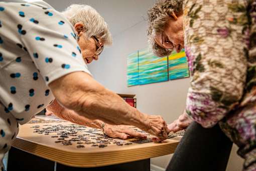 Two women playing a game of jigsaw puzzle.