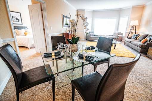 A glass dining table with four chairs in a living room.