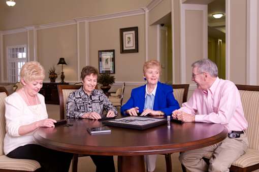 Four people sitting around a table looking at a laptop.