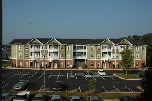 A large apartment complex with a parking lot in front.