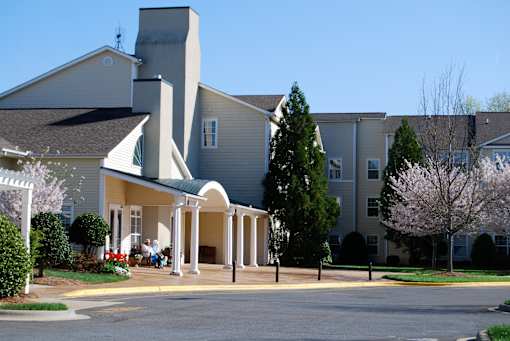 A church with a green roof and a white steeple is surrounded by a parking lot.