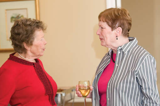 Two women are having a conversation while holding wine glasses.