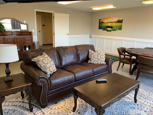 A brown leather couch with a remote on the coffee table.