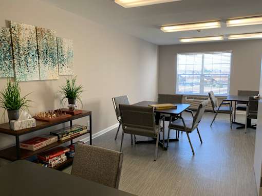 A conference room with a long table and chairs, a plant on a table, and a painting on the wall.
