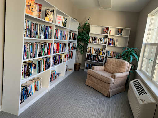 A room with a bookshelf filled with books and a chair in front of it.