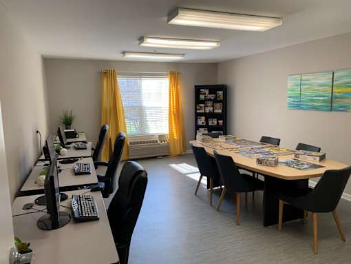 A room with a desk, chairs, and computers.
