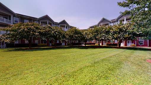 A grassy area in front of a building with trees.