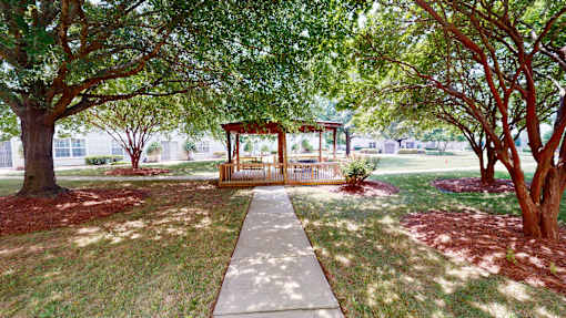 A gazebo is surrounded by trees in a park.