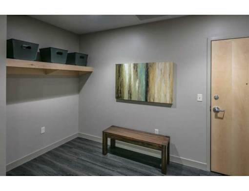 A room with a wooden bench, a painting on the wall, and a door.