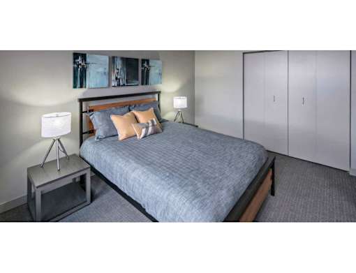 A bedroom with a bed, a nightstand, and a lamp.