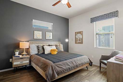 A bedroom with a bed, nightstand, chair, and pictures on the wall.
