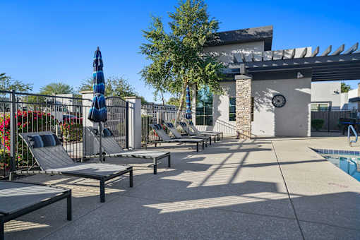 A poolside area with sun loungers and a shade structure.