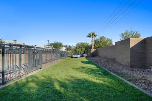 A long grassy area with a fence on the left and a wall on the right.
