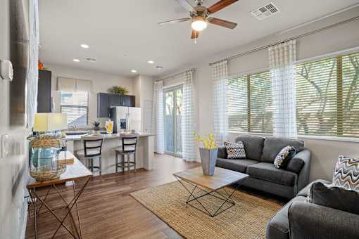 A modern living room with a grey couch and a wooden floor.