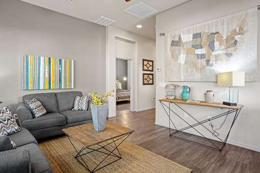 A living room with a grey couch, a coffee table, and a painting on the wall.