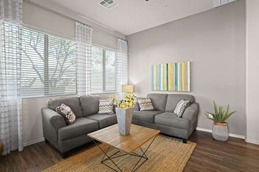 A living room with a grey couch, a coffee table, and a painting on the wall.